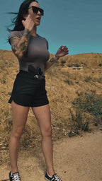 A woman wearing the ALL CORNERS Women's Shorts in black with a holstered pistol in the patent-pending front waistband (holster and firearm not included)